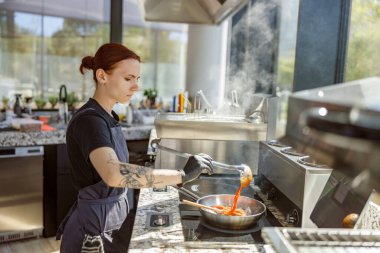 Yetenekli bir şef modern aletlerle donatılmış şık bir mutfakta canlı ve renkli bir yemek hazırlar.