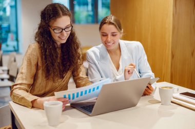 Kendini işine adamış iki profesyonel, dizüstü bilgisayarlar ve detaylı raporlarla donatılmış, son derece verimli bir toplantıya katılıyor.