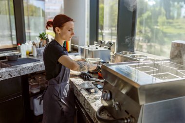 Bir barista, parlak, çağdaş bir kafede ustalıkla içecekler hazırlar.