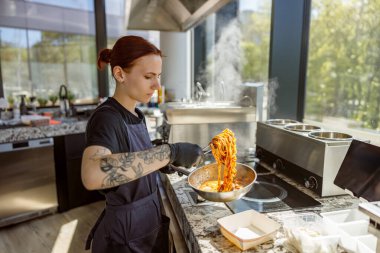 Becerikli bir şef taze makarnayı doğal ışıkla dolu parlak bir mutfağa atar ve enerjik bir hava yaratır.
