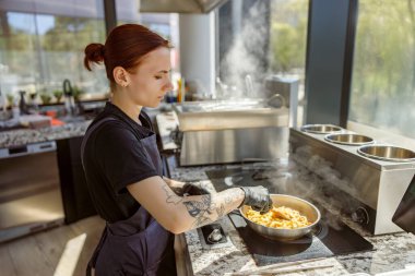 Yetenekli bir şef, buhar ve taze aromalarla dolu modern bir mutfakta makarna hazırlamaya odaklanır.