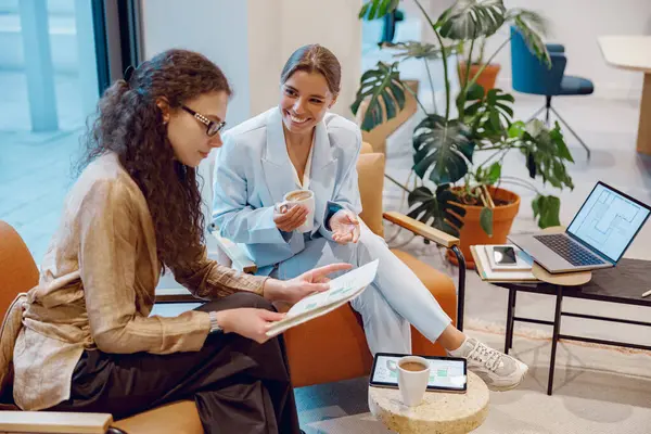 Modern bir ofis ortamında, iki kadın birlikte üretken ve işbirlikçi bir tartışmaya girerler.