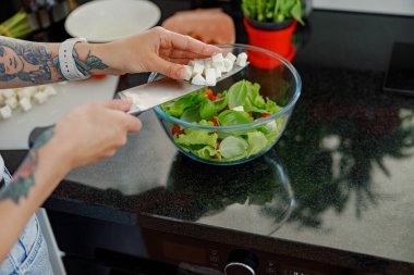 Modern bir mutfakta, yetenekli bir şefin elleri taze, canlı bir salata yapmak için beyaz peynir doğruyor.