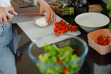 Yetenekli bir şef modern mutfak ortamında canlı sebzeler ve mozarellalar hazırlar.