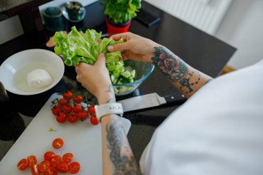 Bir insan şık bir mutfakta besleyici ve sağlıklı bir salata için özenle taze ve renkli sebzeler hazırlıyor.