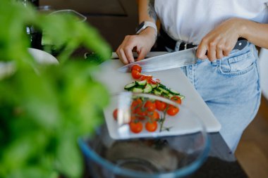 Şık bir mutfakta taze sebzeleri ustalıkla doğrayan bir insan, sağlıklı yemek pişirme alışkanlıklarını teşvik eder.
