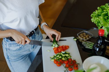 Yetenekli bir insan, parlak ve modern bir mutfakta besleyici bir yemek için renkli sebzeleri heyecanlı bir şekilde doğramaktadır.
