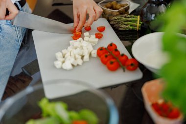 Eller olgun domatesleri ve krem peyniri yakın plan çekimde besleyici bir yemek için ahşap bir tahtanın üzerinde doğruyor.