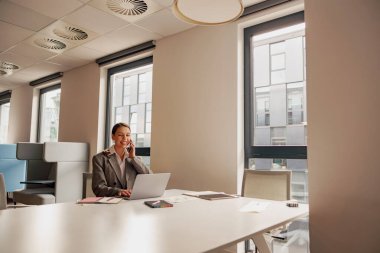 Kendini işine adamış ve odaklanmış bir profesyonel, düzgün ve çağdaş bir ofis alanında özenle bir dizüstü bilgisayar üzerinde çalışıyor.