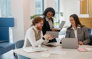 Modern bir ofisteki çeşitli bir ekip, yenilikçi teknoloji ve yaratıcı fikirleri değiş tokuş ederek işbirliği yapıyor.