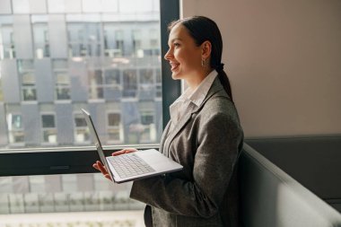 Kararlı ve odaklanmış bir iş kadını, modern ve şık bir ofis alanında özenle dizüstü bilgisayarı üzerinde çalışıyor.