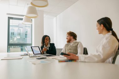 Profesyonellerden oluşan çeşitli bir ekip, parlak ve modern ofis ortamında yenilikçi fikirleri işbirliği içinde tartışıyor.