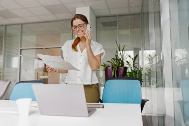 Profesyonel bir kadın, zarif ve modern ofis ortamında aynı anda birden fazla iş yapabiliyor.