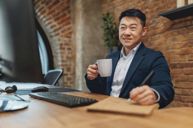 Sadık ve kendini adamış bir profesyonel, modern bir ofis ortamında çalışırken taze demlenmiş kahveden zevk alır.