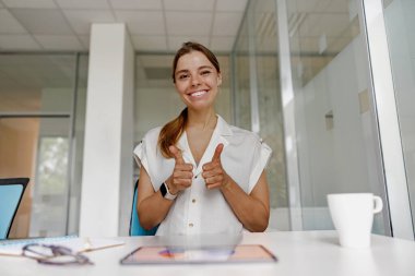 Neşeli bir kadın, modern ofis ortamında pozitif ve kendine güvenini ifade ediyor, coşku saçıyor.