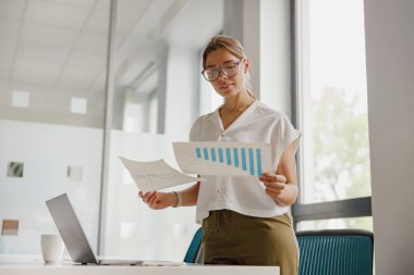 Bir ofiste iş haritaları ve verileri inceleyen, optimal sonuçlar ve görüşleri güvence altına alan odaklı bir profesyonel