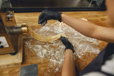 Bir şef hamurdan taze şehriye yapmak için makarna makinesini ustalıkla kullanır..