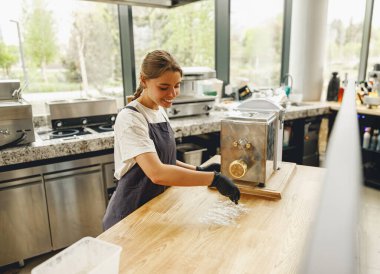 Genç bir şef makarna makinesini ustalıkla modern bir mutfakta kullanır, mutfak sanatını sergiler.