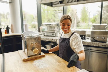 Neşeli bir fırıncı, güzel tasarlanmış ve düzenlenmiş bir mutfak alanında makarnacıyla ustaca çalışıyor.
