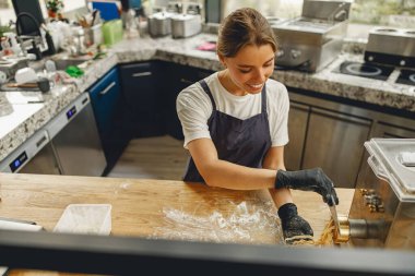 Büyük özen ve titizlikle genç bir kadın şık bir mutfakta bir dizi lezzetli yemek hazırlıyor.
