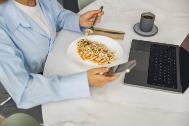 Lezzetli erişteler, şık bir akıllı telefon ve şık bir masada zarif bir dizüstü bilgisayar içeren şık bir iş molası.