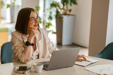 Bir kadın laptopunu şık bir çalışma alanına yerleştirir. Odaklanma ve üretkenlik yeteneklerini gösterir.