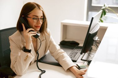 Profesyonel bir kadın, modern iş yerinde uzmanlığını sergilemek için bir telefon görüşmesi yapıyor.