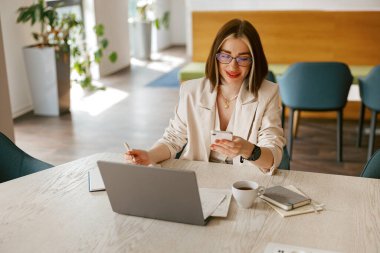 Meşgul profesyonel bir kadın, modern ve şık bir çalışma alanındaki önemli görevlerine özenle odaklanır.