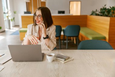 Şık bir çalışma alanında telefonda neşeli bir kadın profesyonellik, verimlilik ve yaratıcılık sergiliyor.