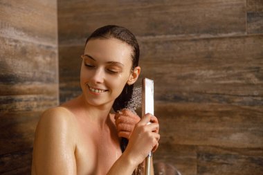 Sıcak bir duşta duran bir kadın, gerçekten ferahlatıcı bir anı kucaklarken güzel saçlarıyla nazikçe ilgilenir.