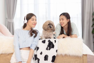 Asian female friend having fun with dog in bedroom.