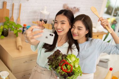 Spor giyim sektöründe aktifleşen Asyalı iki kadın mutfakta sağlıklı yiyecekler yiyor..