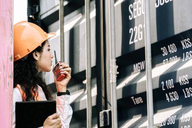 Kargo konteynerlerindeki kadın işçilerin portresi. Kadın elinde telsiz ve dijital tablet tutuyordu..
