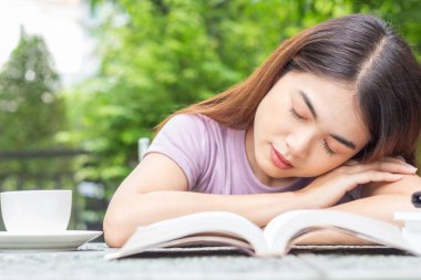 Close-up front view of Asian woman reading a book in the backyard show many emotions