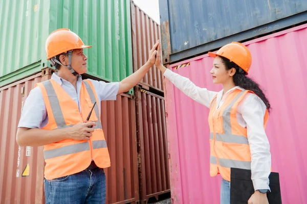 Team of logistics engineers, men and women in reflective jackets stand outside large commercial port. Containers in Export-Import Business and Logistics.