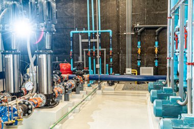 Korumalı üniformalı Asyalı işçi ve kasketli. Boru fabrikasındaki sıcaklığı ölçmek için tablet kullanıyor.