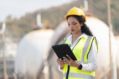 Petrokimya fabrikası geçmişi olan kadın mühendis. Tablet, plan ve telsiz taşıyan Asyalı kadın..