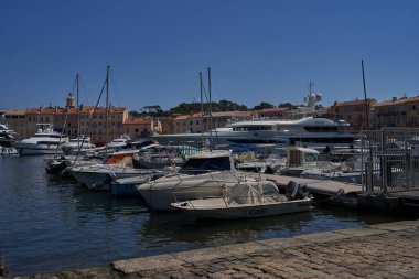  Saint-Tropez, Fransa - 8 Ağustos 2022 - Lüks yatlar, botlar ve yelkenliler eski kasaba bölgesindeki liman marinası, dükkanlar ve kafeler arasında yer alıyorlar.                                      