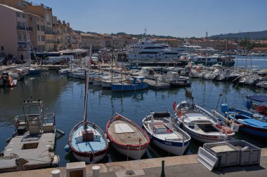  Saint-Tropez, Fransa - 8 Ağustos 2022 - Lüks yatlar, botlar ve yelkenliler eski kasaba bölgesindeki liman marinası, dükkanlar ve kafeler arasında yer alıyorlar.                                      