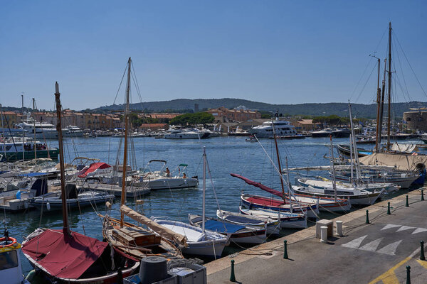  Saint-Tropez, France - August 8, 2022 - luxury yachts, boats, and sailboats line the port marina opposite shops and cafes in the old town area                                      
