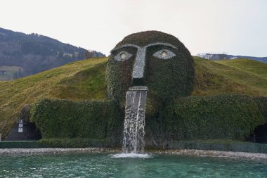 Wattens, Avusturya - 18 Mart 2023 - Swarovski Kristallwelten 'deki gölete su tüküren dev başlı bir çeşme                                  