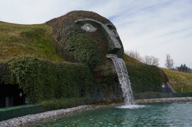 Wattens, Avusturya - 18 Mart 2023 - Swarovski Kristallwelten 'deki gölete su tüküren dev başlı bir çeşme                                  