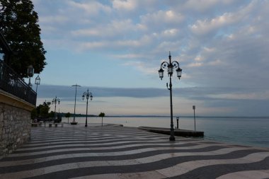 Lazise, İtalya - 15 Haziran 2024 - Garda Gölü 'nde büyülü bir sabah. Lazise 'de boş gezinti güvertesi                               