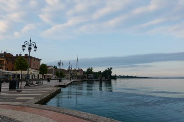Lazise, İtalya - 15 Haziran 2024 - Garda Gölü 'nde büyülü bir sabah. Lazise 'de boş gezinti güvertesi                               