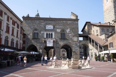  Bergamo, İtalya - 17 Haziran 2024 - güneşli bir bahar sabahı Yukarı Kasaba 'nın en ünlü meydanı olan Piazza Vecchia' daki Contarini çeşmesi                              