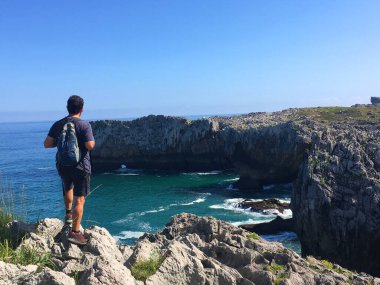 Arkasını dönmüş biri Llanes yakınlarındaki Cantabrian sahiline bakıyor. Asturyalar. İspanya