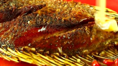 Kızarmış tilapia balığının üzerine sos dökmek, Tayland 'ın ünlü yemekleri..