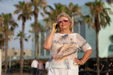 Güneş Gözlüklü Şık Yaşlı Kadın Yazın Deniz kenarında Cep Telefonuyla Konuşuyor