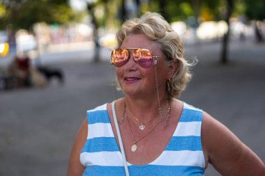 Mavi beyaz çizgili tişörtlü güneş gözlüğü takan bir kadın.