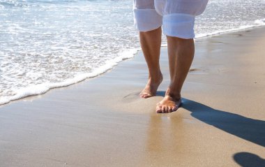 Güneş gözlüklü son sınıf kadın Los Angeles sahilinde yürümekten zevk alıyor.